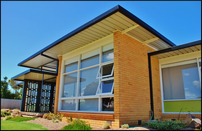 The floating rooflines, expanses of glazing, breezeblock entry screen and bold colours all distinguish the house.